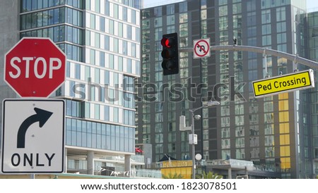 Traffic light and caution sign, road intersection in USA. Transportation safety, rules and regulations symbol. Driveway crossing attenion signal against modern urban cityscape, San Diego, California.