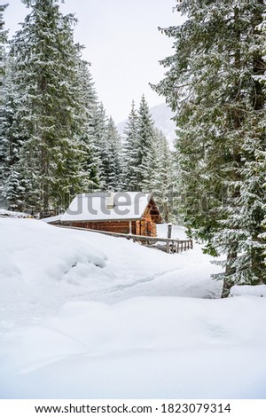 Wooden house in winter mountain landscape. Cottage / Hut in snowy mountains. Travel destination for recreation.