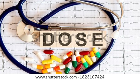 Wooden blocks with the inscription DOSE with stethoscope,pills