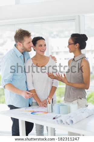 Interior designer speaking with happy clients in creative office