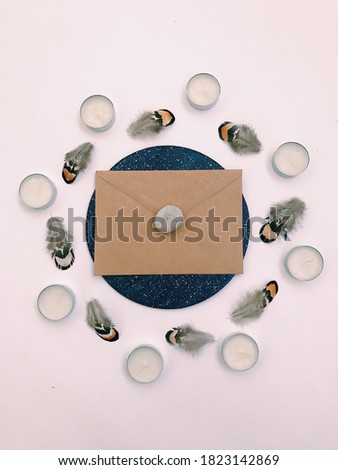 Feather texture background, layout for text. Beautiful magic background of natural objects, an unusual combination. Natural small striped feathers, craft envelope, white tea candles