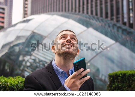 Photo of a young and attractive business man wearing smart casual clothes sending and audio with is phone in a job break