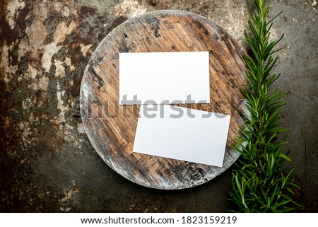 Photo of blank white business cards on a dark wooden cutting board circle. Blank template for brand identity mock-up design, food theme. Presentation and portfolio template