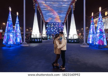 couple in love at night on a square decorated with lamps on Christmas Eve