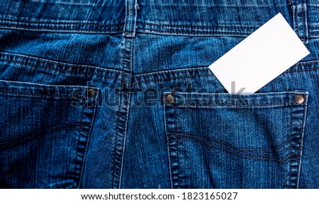 Photo of blank white business card sticking out of blue jeans pocket. Blank template for brand identity mock-up design. Presentation and portfolio template