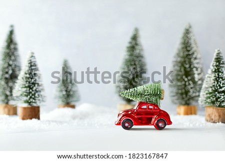 Cute winter holidays concept with retro car transporting Christmas tree, front view of artificial winter  setting 