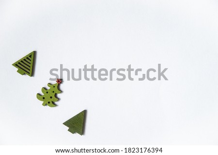 three green toy wooden Christmas trees on a white background with a place to insert text