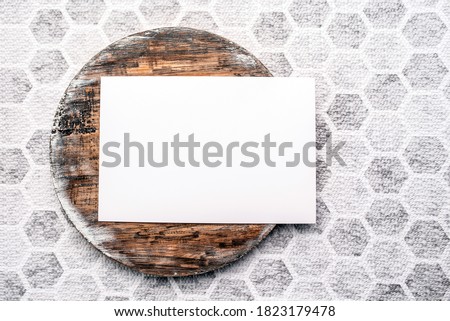 Photo of blank white card on a dark wooden cutting board circle. Blank template for brand identity mock-up design, food theme. Presentation and portfolio template
