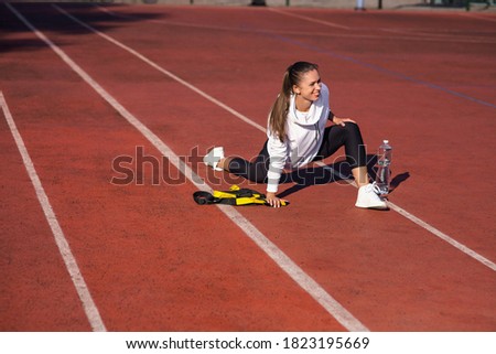 Sporty young girl warming up before training on the playground on a sunny day