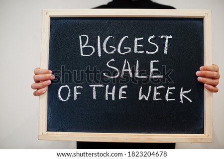 Biggest sale of the week written on blackboard. Black friday concept. Boy hold board.