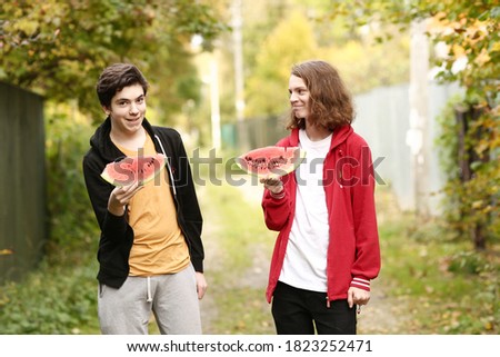 two teenager boys with water melon slices close up photo on fall background