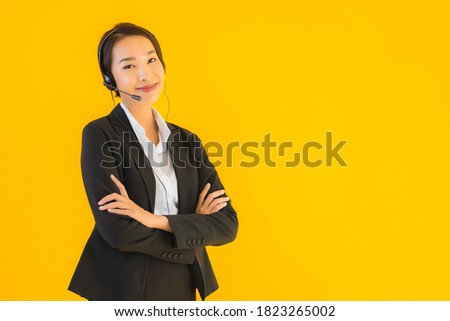 Portrait beautiful young business asian woman with headphone or headset for call center or telemarketing on yellow isolated background