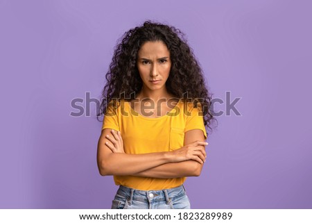 Grumpy Woman. Portrait of serious offended lady standing with crossed arms, posing over purple studio background, feeling angry and displeased, having bad mood, looking at camera, copy space Royalty-Free Stock Photo #1823289989