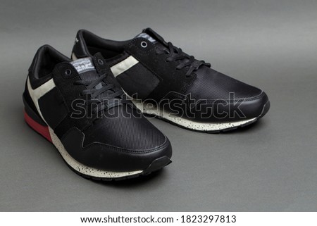 Pair of stylish black sneakers on a gray background. Insulated footwear.