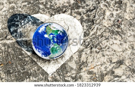 Earth in white heart shape on dirt, Giving Love to our World Concept, Elements of this image furnished by NASA