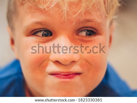Close up portrait cute smiling blue eyed freckled blond boy pronounced artistic facial expressions, gestures, intriguing cunning funny mischievous. Happy childhood, children behaviour problems concept