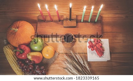 Kwanzaa holiday concept with decorate seven candles red, black and green, gift box, pumpkin,corn and fruit on wooden desk.
