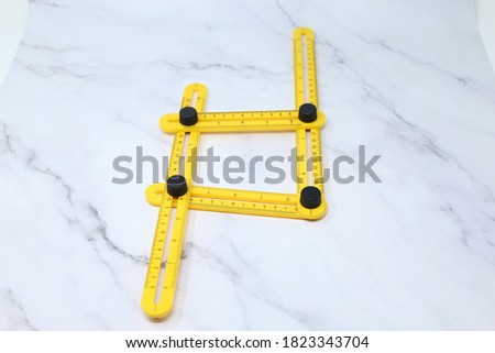 Yellow multi function Ruler isolated on grey background. Ultimate Irregular Shape Copy Tool. Universal Easy Angle Ruler. Multi Angle Measuring Tool.