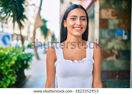 Young latin girl smiling happy walking at street of city.