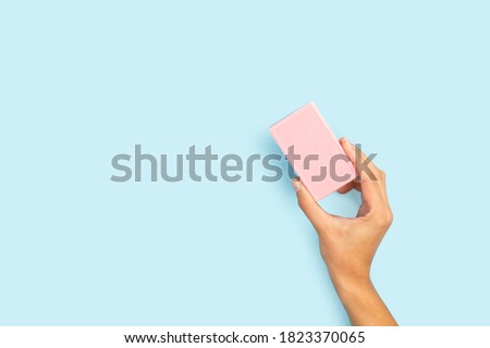 Woman hand holding a pink soap bar on a light blue background with copy space Royalty-Free Stock Photo #1823370065