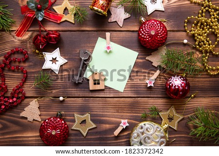 Christmas flat lay on a wooden background with keys to a new house in the center with a place for notes. New year, transfer, shares of the mortgage, the rental of a cottage. Space for text, to do list