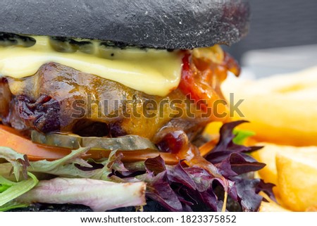Modern delicious black burger with meat, bun, lettuce, cheese, ketchup. Funk food concept. Macro. Selective focus