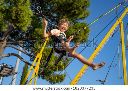 Children have fun jumping on bungee trampoline secured with rubber bands.  Royalty-Free Stock Photo #1823377235