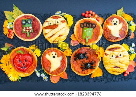 Halloween pizza with cheese, olives and ketchup. Decorated mummy, ghost, spiders, zombie, pumpkin. Funny crazy food for kids.