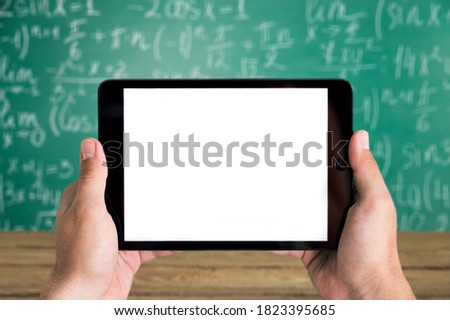 Teacher hosting digital tablet with a blank screen on the blackboard background