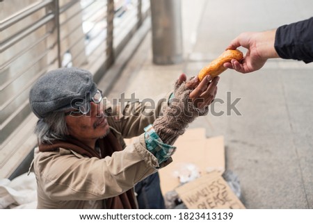 Aged homeless beggar reach out to get bread on donor hand at corridor bridge