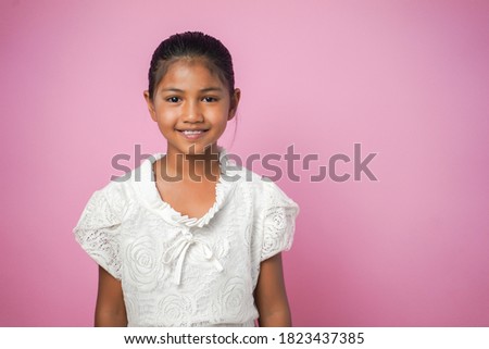 Portrait of happy smiling asian child girl isolated on pink background.