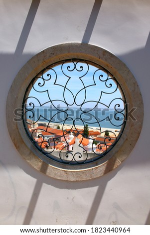Circular window with ornate metal grid and views over the city and river