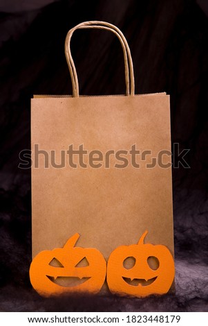 Shopping Halloween, paper, craft shopping bag with a pattern of orange pumpkins on a black spider web background.
