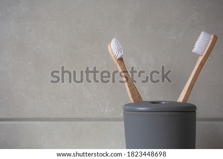 Eco Friendly bamboo natural organic toothbrushes in grey holder, with natural colored stone tiles bathroom wall background texture close-up