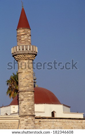 Minaret and Mosque with red roofs and palm trees in Rhodes, Greece