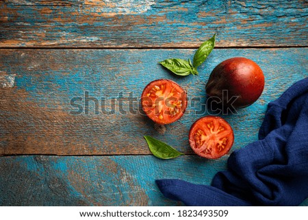 Large black tomato halves on a vintage wooden background, top view