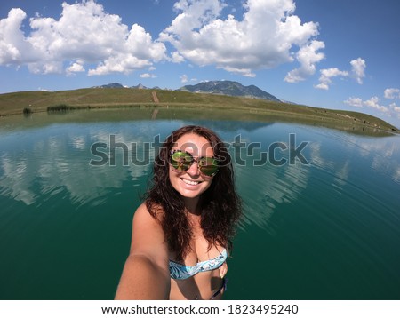 Beautiful young girl is doing selfie on stand up paddle