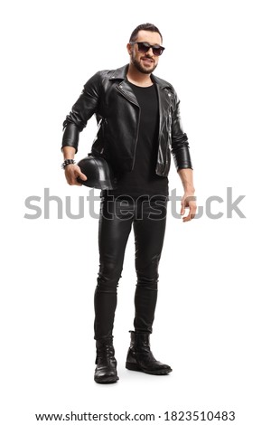 Full length portrait of a biker in leather jacket and pants holding a leather helmet isolated on white background Royalty-Free Stock Photo #1823510483