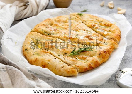 Garlic foccacia bread. Freshly baked flat garlic bread, olive oil and herbs. Royalty-Free Stock Photo #1823514644