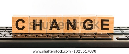 change word made with building blocks. A row of wooden cubes with a word written in black font is located on a black keyboard.
