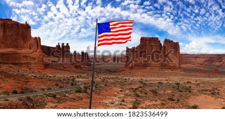 American National Flag. Panoramic landscape view of a Scenic road in the red rock canyons. Blue Sky and White Clouds. Taken in Arches National Park, located near Moab, Utah, United States.