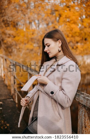beautiful long-haired woman walks through the autumn streets. Railway, autumn, woman in a coat.