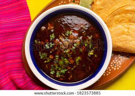 Traditional mexican birria consome soup and tacos on yellow background