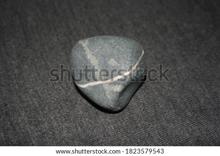 Wishing Stones. Stones with Lines Through Them. White line through pinkish grey rock. smooth rock. Stone Isolated on Grey Cotton Knit Background. Grey Fabric backdrop. Pebble isolated. Macro stone.