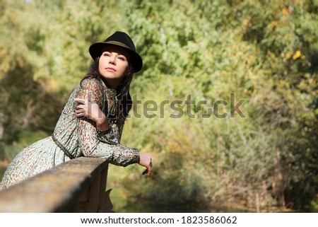 Beautiful young woman in a hat is resting in the park. Natural background.