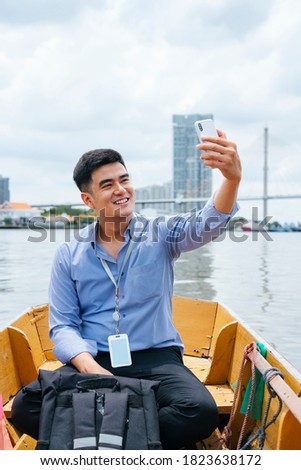 Asian business man taking photo with smartphone and travel by a boat in Bangkok.