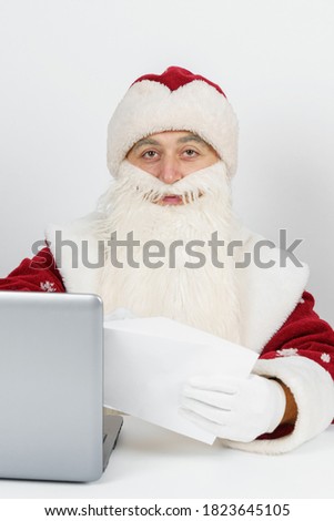 Christmas and New Year concept. Santa Claus is sitting at his desk and reading letters.