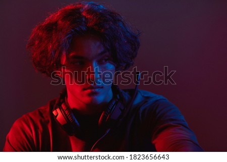 Close-up of young gamer in headphones playing computer games in dark room