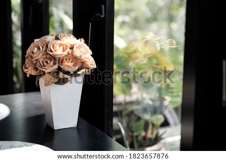 Dry rose Decorated in white vase Put it on a black table by the window. Stabilized flowers in a white ceramic vase. Interior decor.