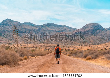 A young man walking along a desert path in the natural park of Cabo de Gata, Nijar, Andalusia. Spain, Mediterranean Sea Royalty-Free Stock Photo #1823681702